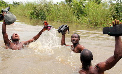 FLOOD PUTS S/SOUTH ASUNDER: Mortuary attendants stack corpses on roof tops