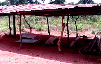 Pupils learn under makeshift tatty structures, trees and sandy floors