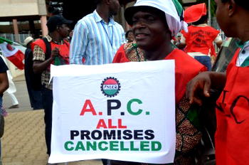Worker carries placard changing  “APC ” to “All Promises Cancelled”