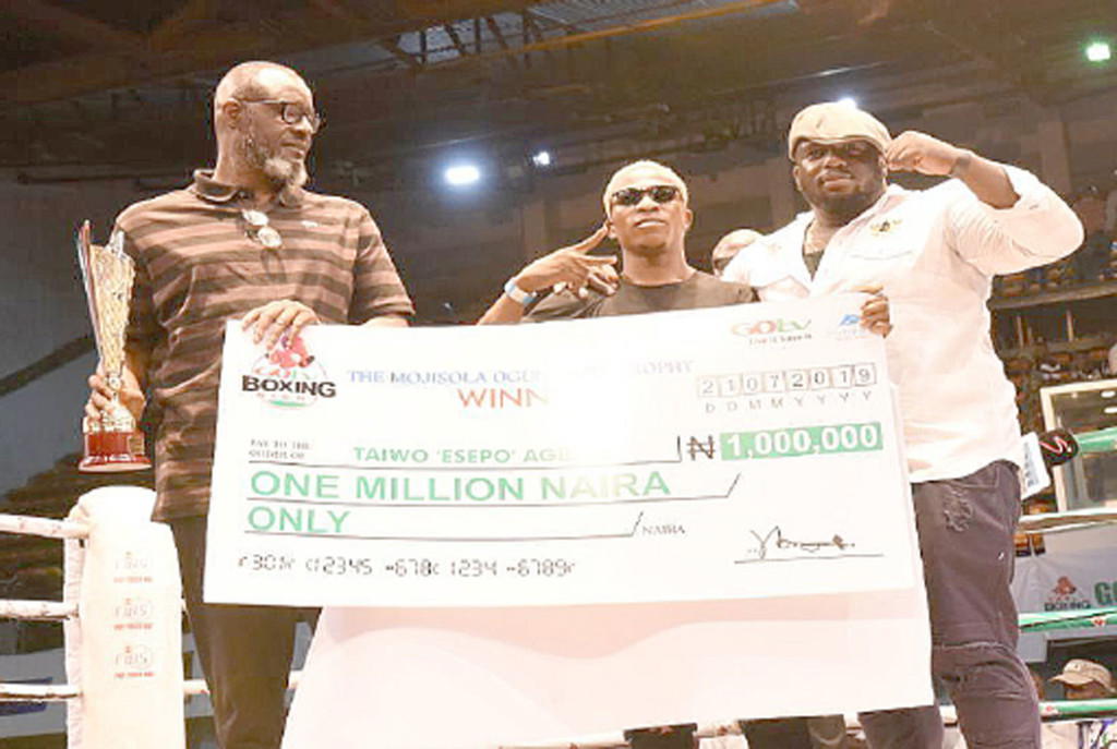 L-R: Vice President, Nigeria Basketball Federation, Babs Ogunade, Taiwo ‘Esepo’ Agbaje and his manager, Ajibade Ogunjokun after the boxer was presented with the Mojisola Ogunsanya Memorial Trophy and the N1m cheque replica.