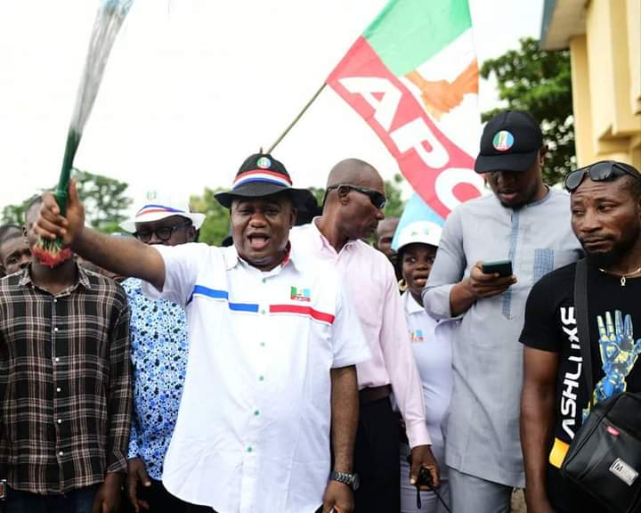 Chris Agara in white shirt with the symbolic APC broom