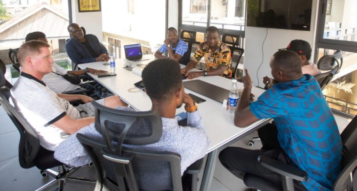 Wide-angle shot of a strategy meeting at Sporting Lagos offices involving Luke Dowling and club executives.