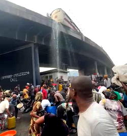 Residents scoop fuel as a diesel tanker falls at Tincan Liverpool Bridge